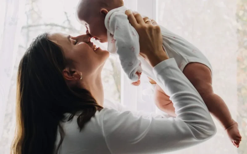 New mother applying gentle skincare in bathroom mirror