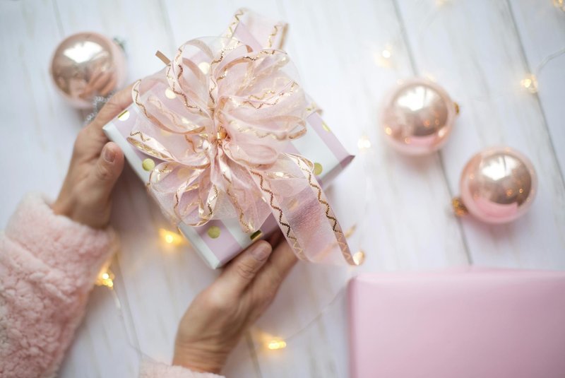 Woman holding wrapped Christmas gift with pink ornaments