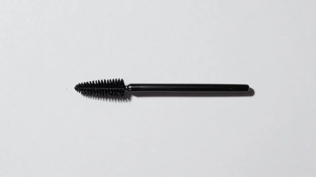 Black mascara wand with bristles on a white background