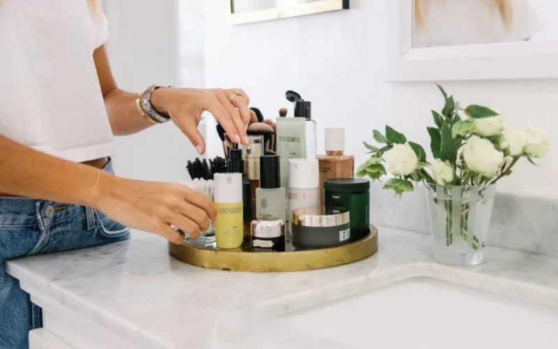 Hands arranging skincare products on a gold tray